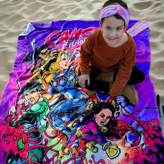 Fleece superhero blanket being used to sit on at the beach